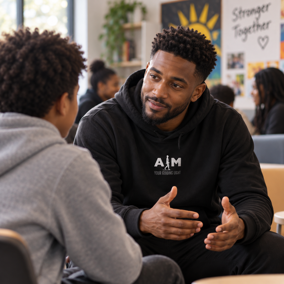 Illustrative AIM community conversation with two people speaking and listening, one wearing subtly branded AIM apparel.