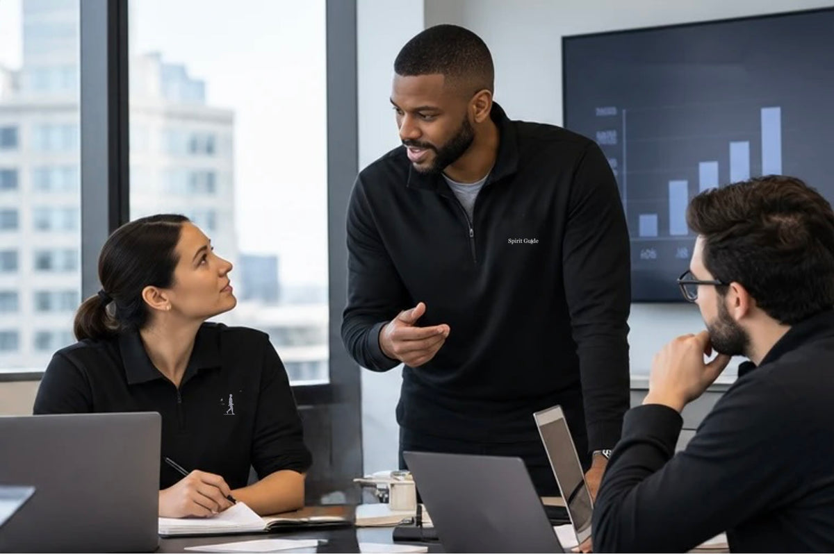 Illustrative AIM business collaboration: colleagues in subtly branded workwear listening and discussing a project in an office.