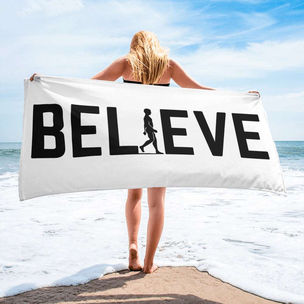 A white AIM ATTITUDE Believe Towel with black text, showing the soft fabric and printed logo design.