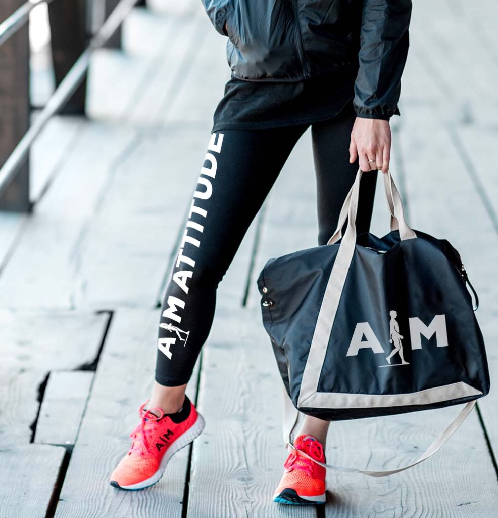 A confident individual showcasing "Style and Self-Esteem" through their athletic apparel, featuring leggings with "AIM ATTITUDE" branding, complemented by a matching duffel bag and vibrant red sneakers, embodying an active and positive lifestyle.