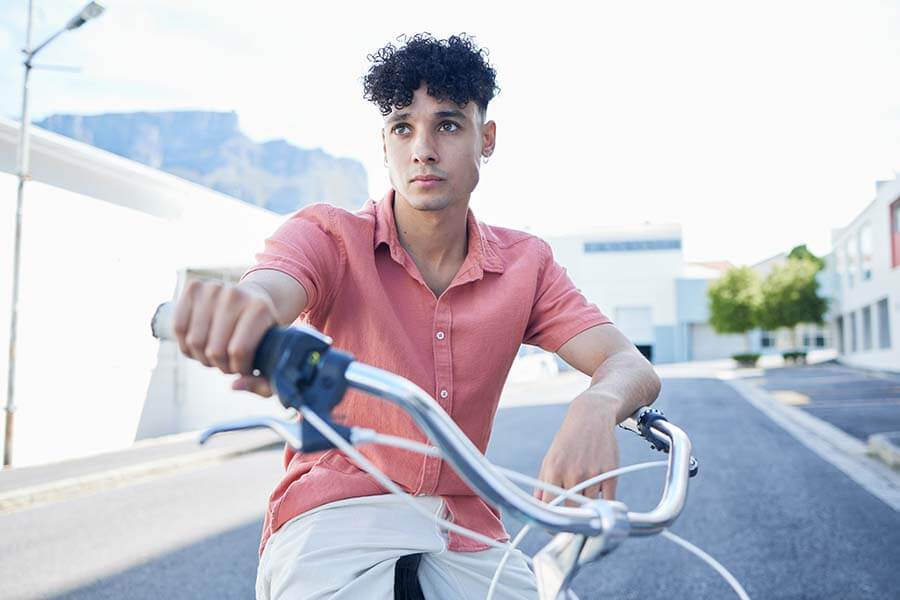Focused young man riding a bicycle, representing an eco-friendly lifestyle and the intersection of style and self-esteem.