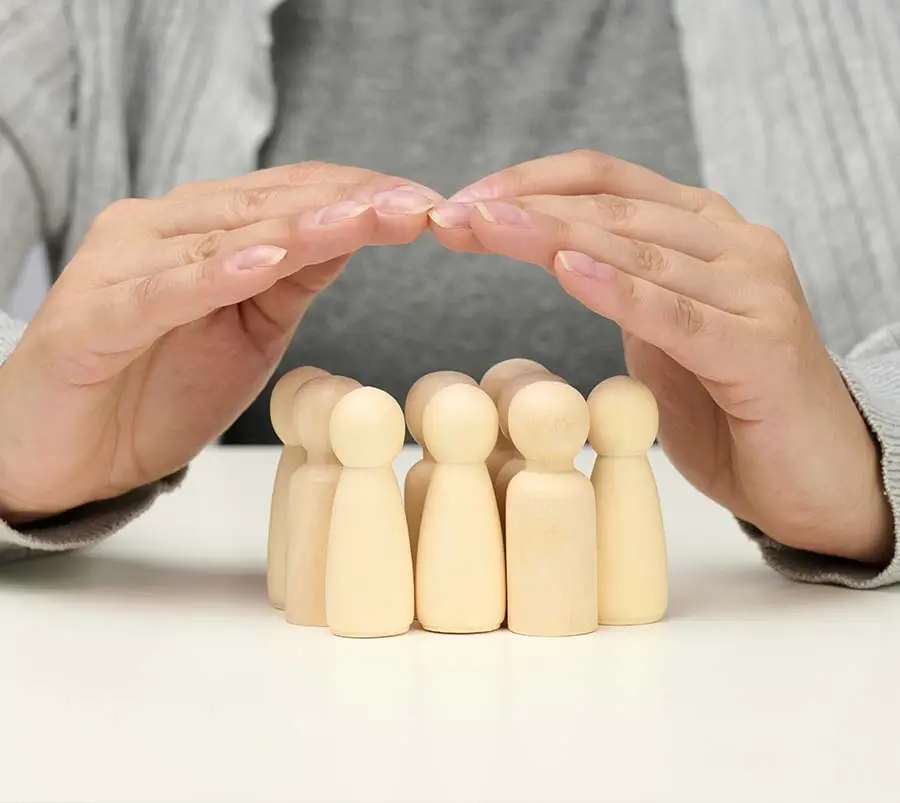 Wooden figurines representing a family, with two larger figurines forming a protective arch over a group of smaller ones, illustrating the concept of support and security in family dynamics, which is essential for mental health and emotional wellness.