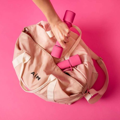women-sports-bag-with-dumbbells-lying-on-pink-back-WQXSSBY